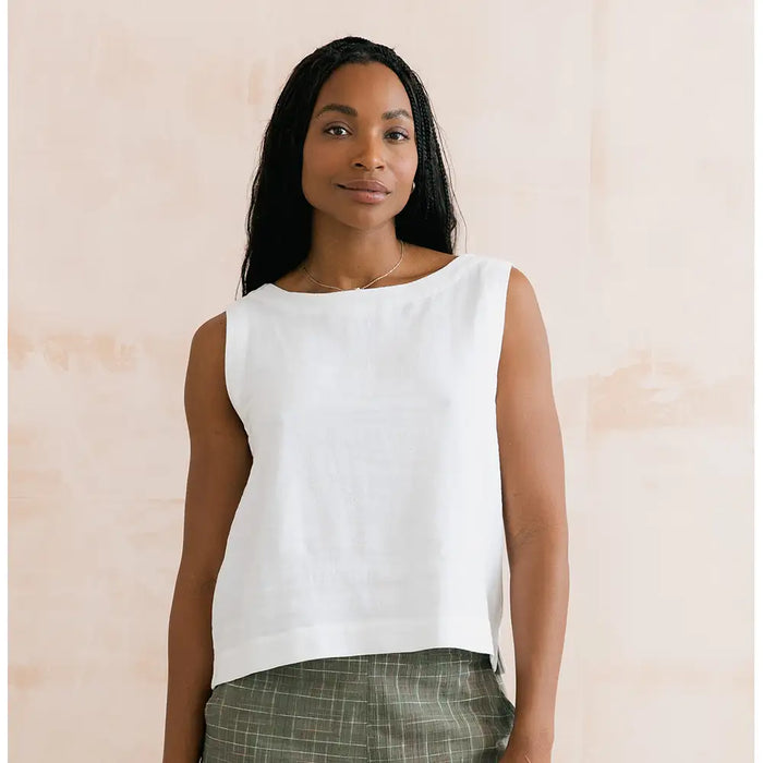 Woman wearing a white sleeveless top against a beige background