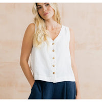 Woman wearing a white sleeveless button-up top with a beige background