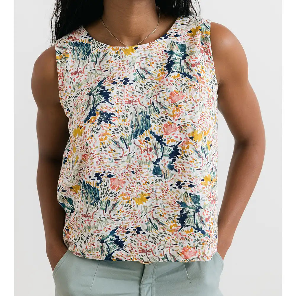 Person wearing a sleeveless floral top on a white background