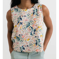 Person wearing a sleeveless floral top on a white background