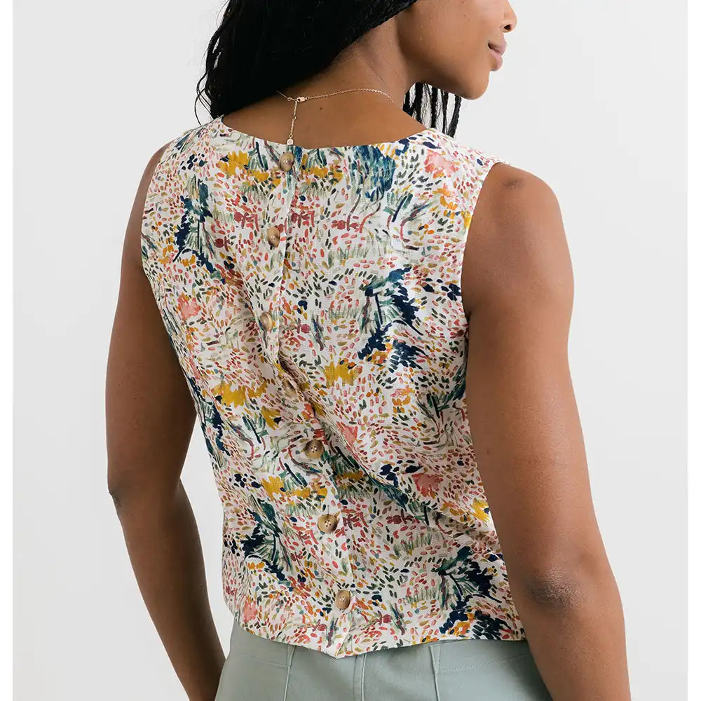 Woman wearing a sleeveless floral top against a white background