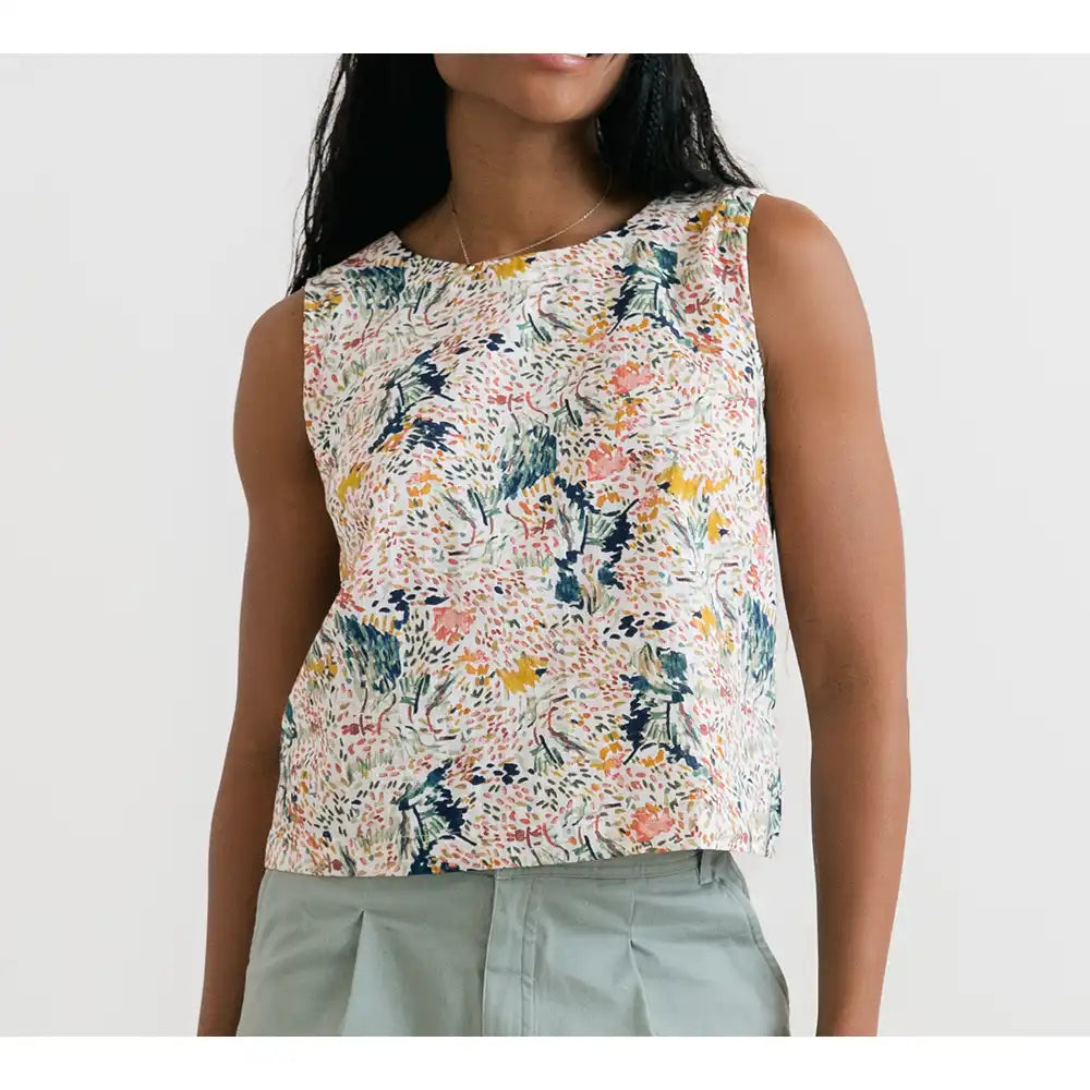 Woman wearing a sleeveless floral top against a white background