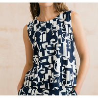 Woman wearing a sleeveless top with a geometric pattern on a beige background