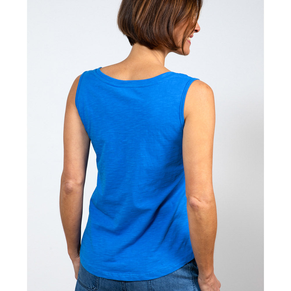 Female with short brunette hair wearing a strong bright blue vest top with wide shoulder straps and a high round neckline at the nape of the neck