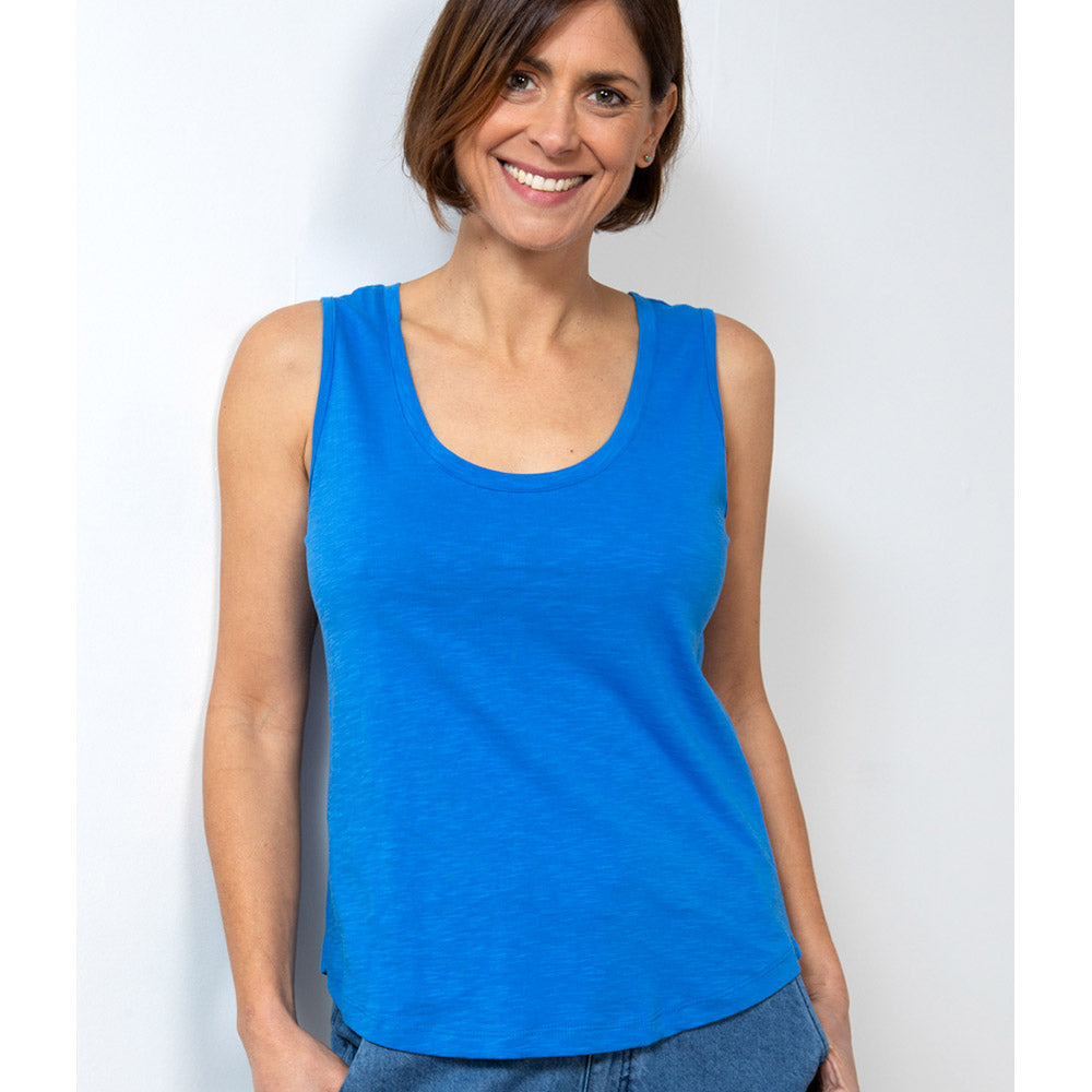Female with short brunette hair wearing a bright strong blue vest with wide shoulder straps and a round neckline 