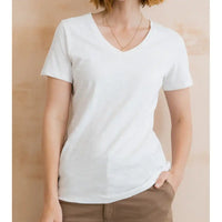 Person wearing a plain white t-shirt against a beige background
