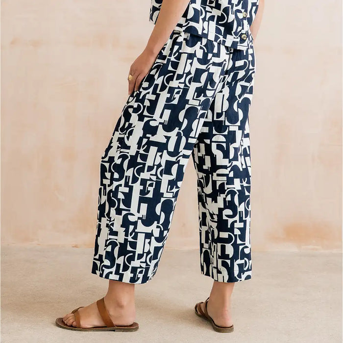 Person wearing navy and white patterned pants on a beige background