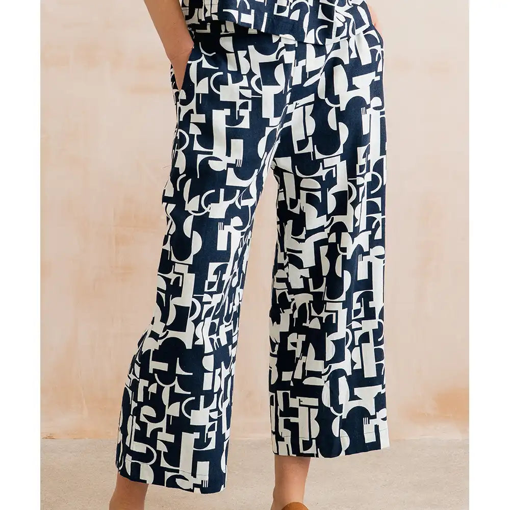 Navy blue and white patterned pants worn by a person on a beige background