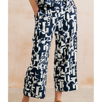 Navy blue and white patterned pants worn by a person on a beige background