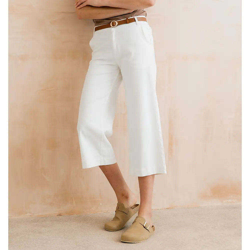 Person wearing white pants and beige shoes against a beige background