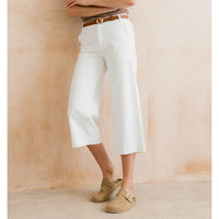 Person wearing white pants and beige shoes against a beige background