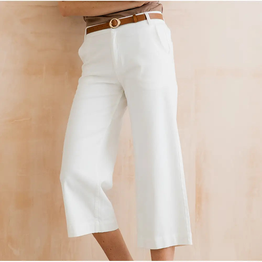 White wide-leg pants with a brown belt on a beige background