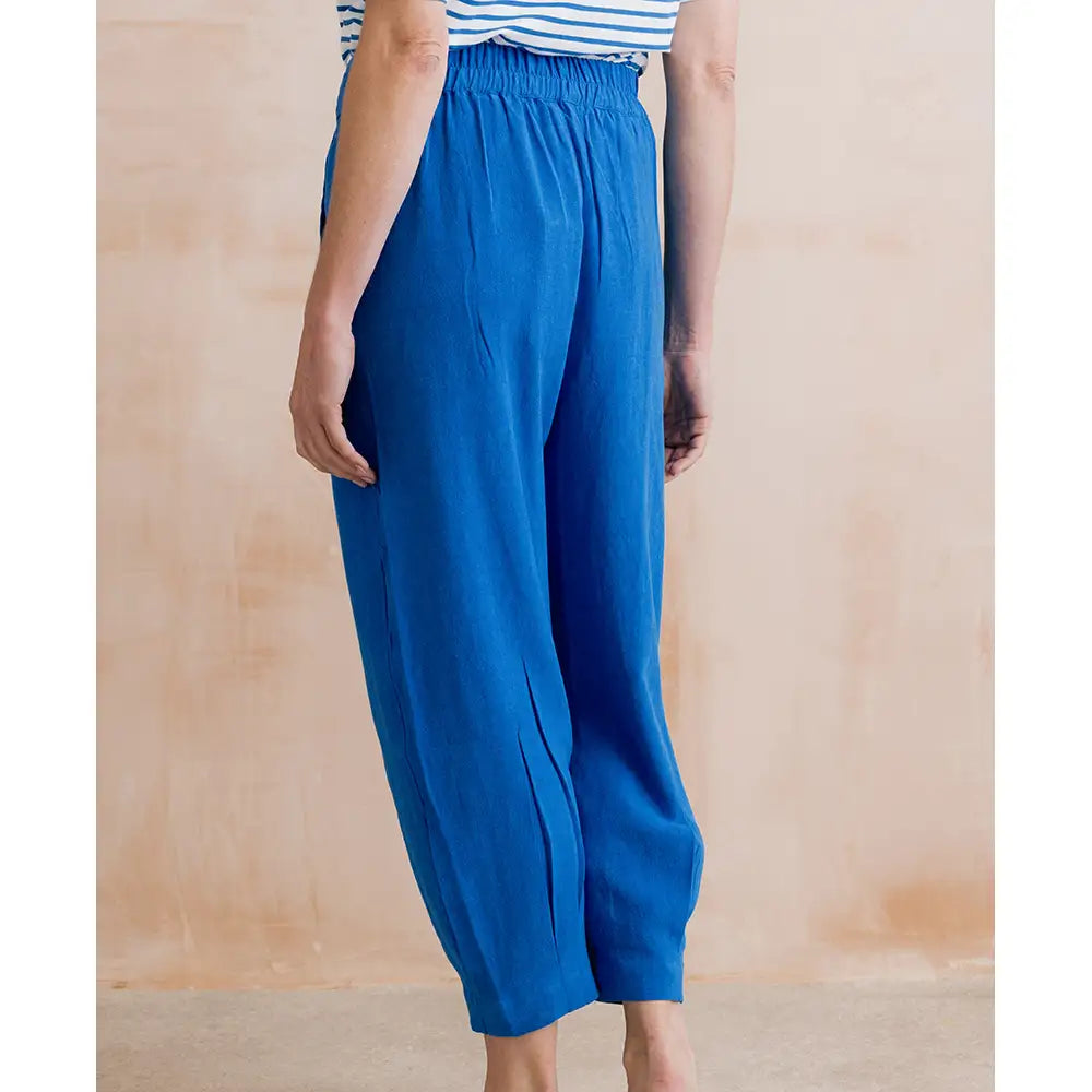 Person wearing blue wide-leg pants against a beige background