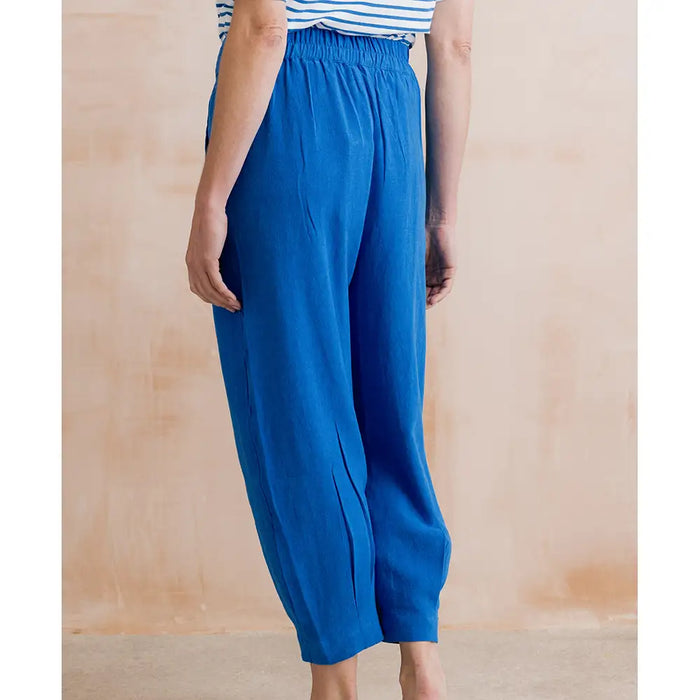 Person wearing blue wide-leg pants against a beige background