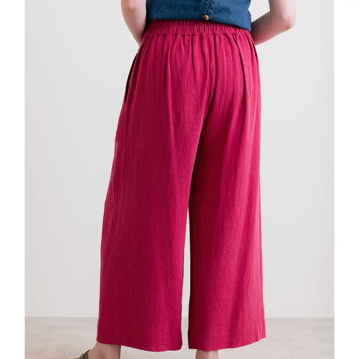 Person wearing bright pink wide-leg pants with a plain background