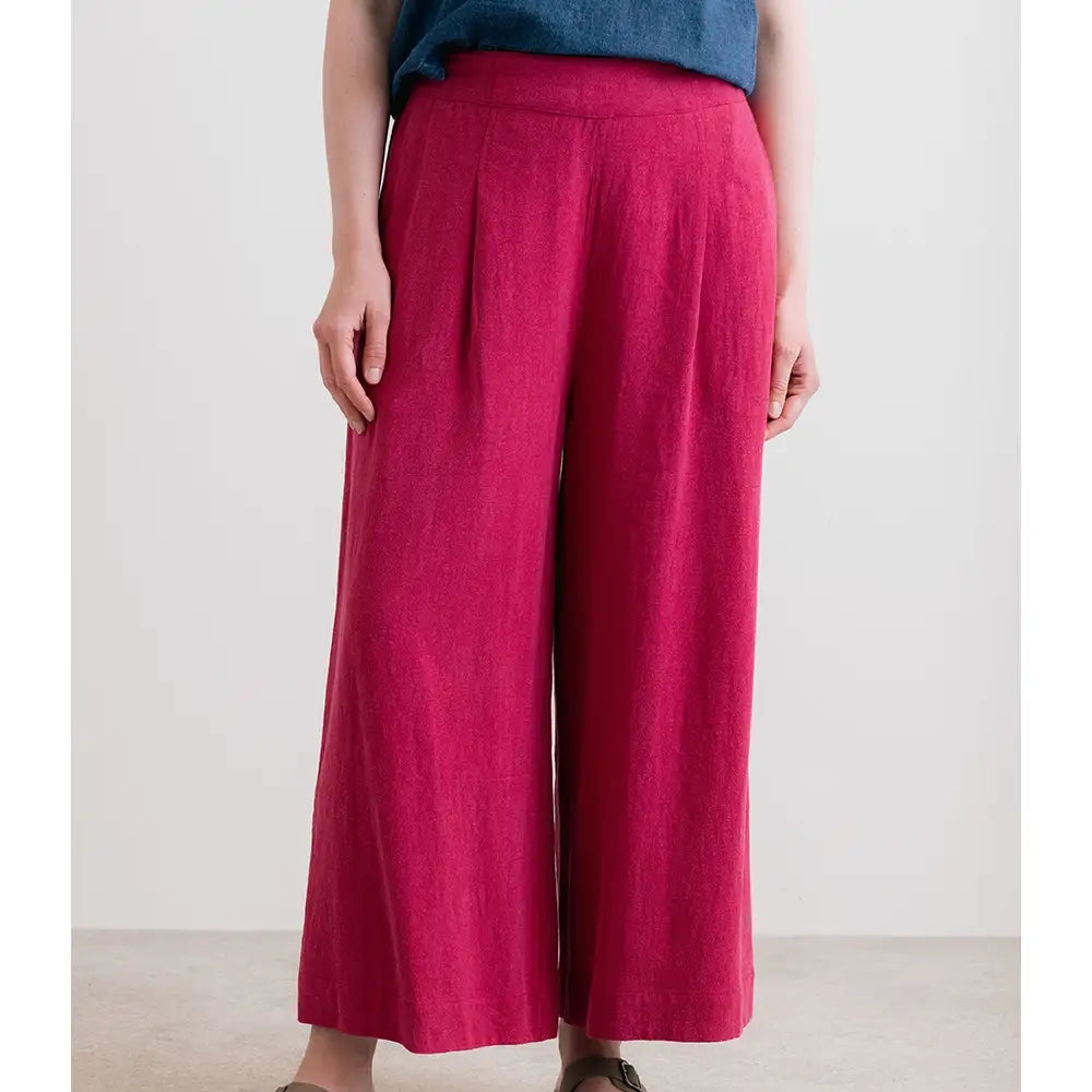 Person wearing magenta wide-leg pants with a plain background