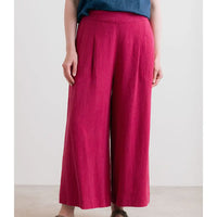 Person wearing magenta wide-leg pants with a plain background