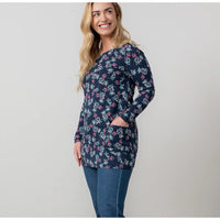 Woman wearing a navy floral patterned long-sleeve top on a light gray background