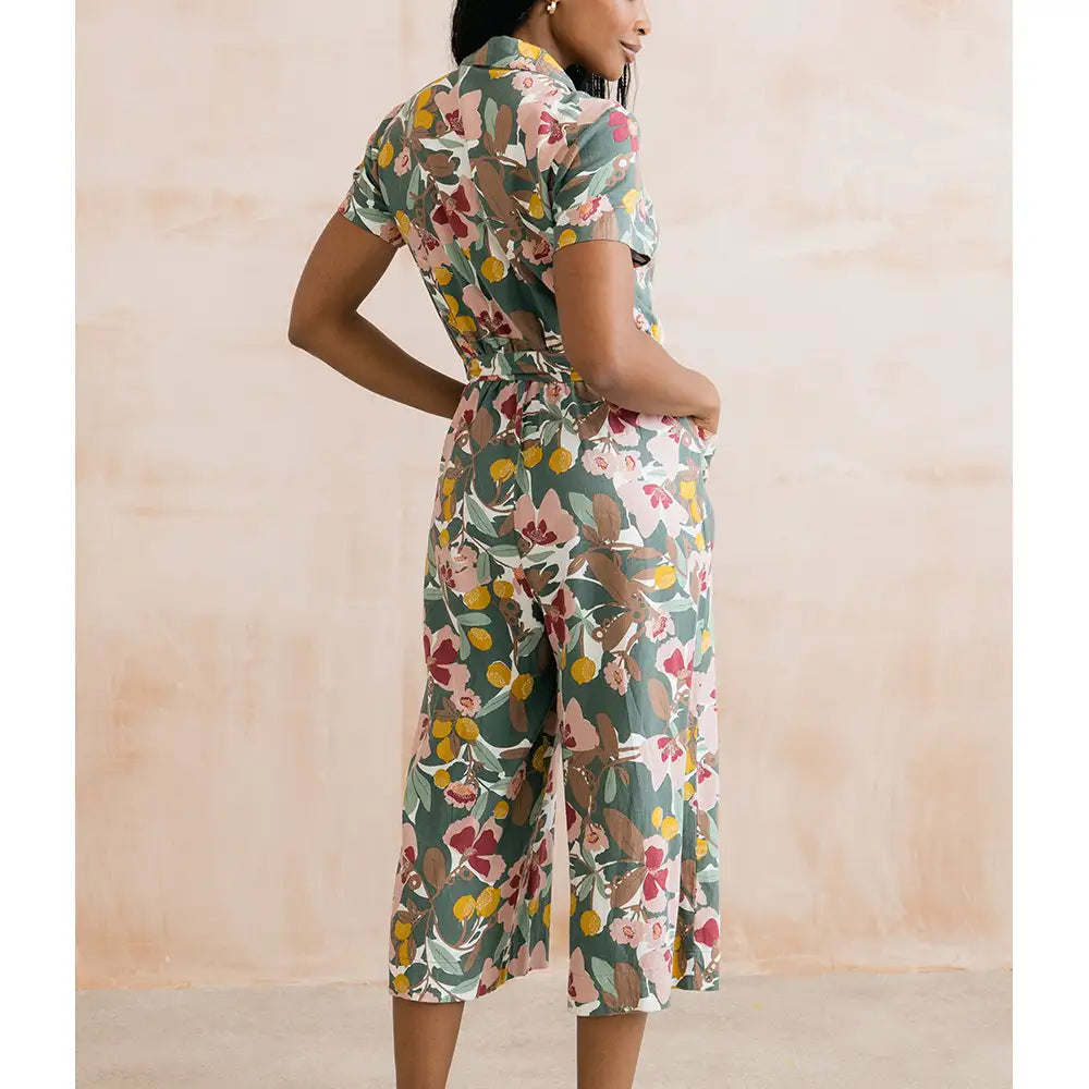 Woman wearing a floral jumpsuit against a beige background