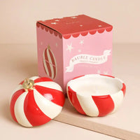 A scented bauble candle set with a red and white striped spherical lid and matching bowl, shown next to its pink packaging box.
