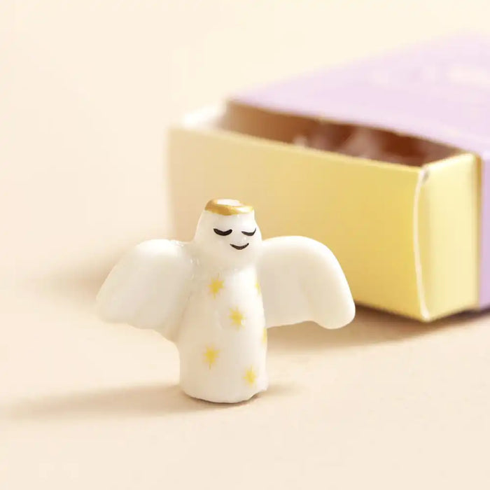 Small angel figurine with a gold halo on a beige background
