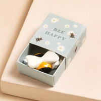 Ceramic bee  in a 'Bee Happy' box on a beige surface