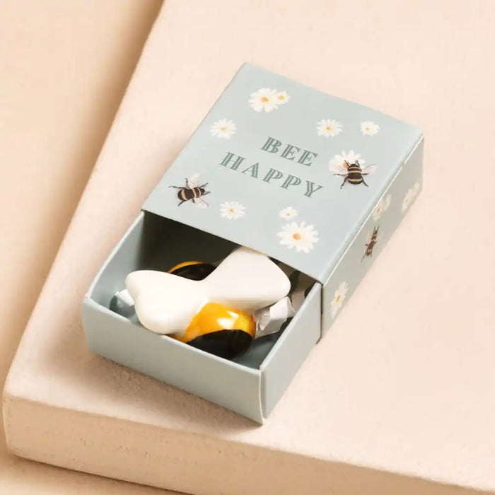 Ceramic bee  in a 'Bee Happy' box on a beige surface
