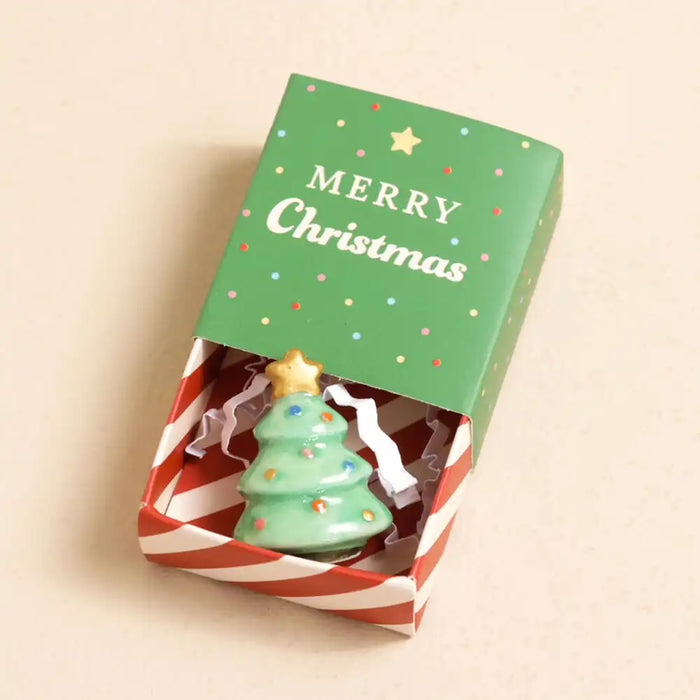 Christmas-themed ceramic token with a tree design in a decorative box on a beige background