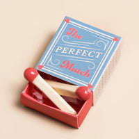 Decorative match stick  ornament in a box with "The Perfect Match"  printed on the box, on a beige background