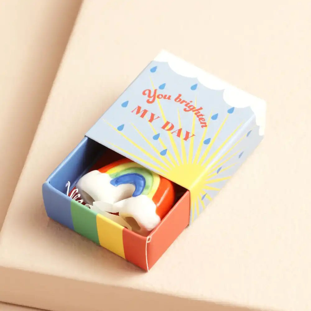 Colorful matchbox with rainbow design ceramic token inside and 'You brighten my day' text on a beige background