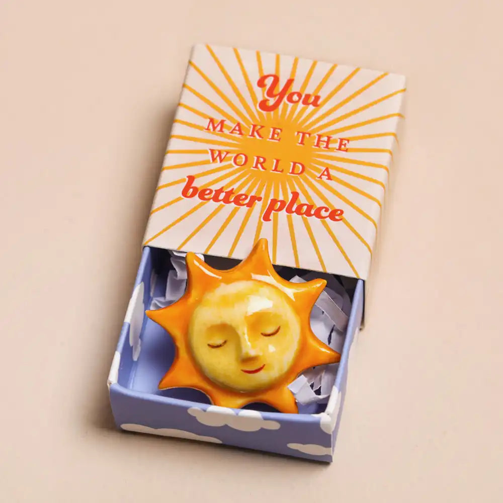Decorative sun ornament in a box with a motivational quote on a beige background