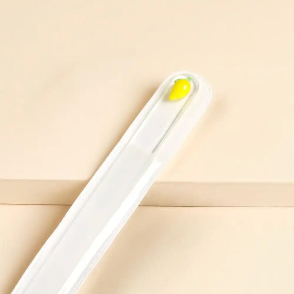 Glass nail file with glass lemon charm decoration on a beige background.