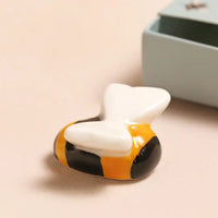 Bumblebee ceramic figurine on a beige surface with a gray box in the background
