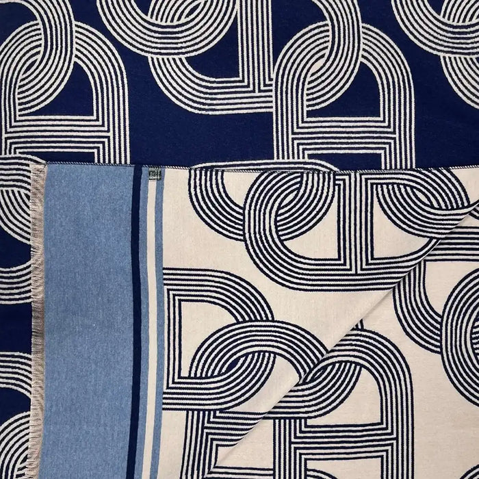 A navy blue scarf with a white geometric interlocking pattern and a light blue borde