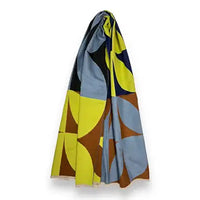 A lightweight scarf with a bold mid-century modern geometric pattern in yellow, light blue, brown, and black, draped against a plain white background.