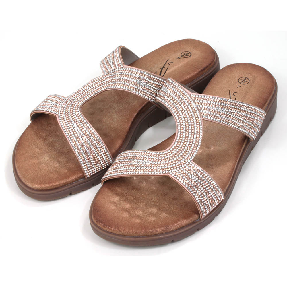 Slider sandals with low heels. Tan coloured footbeds and soles. Diamante covered straps with a combination of rose gold and silver jewels. Angled view.