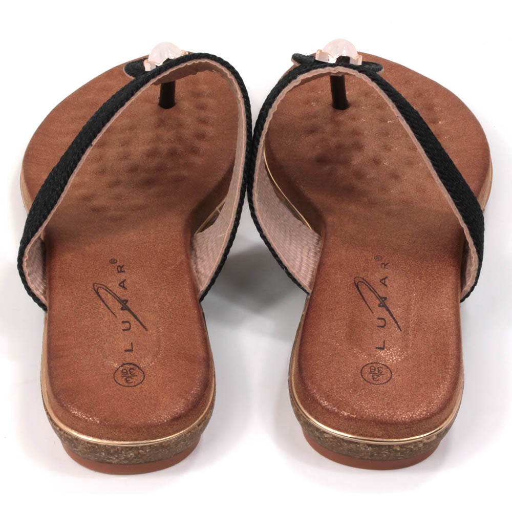 Flat toe post sandals in black with tan coloured textured footbed. Straps in textured fabric and featuring a gemstone centred over the foot. Back view.