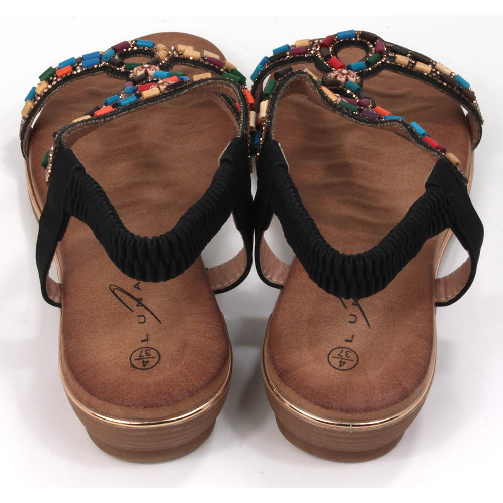 Strappy sandals with elasticated ankle strap in black. Decorated with colourful beads. Tan coloured footbeds. Flats. Back view.