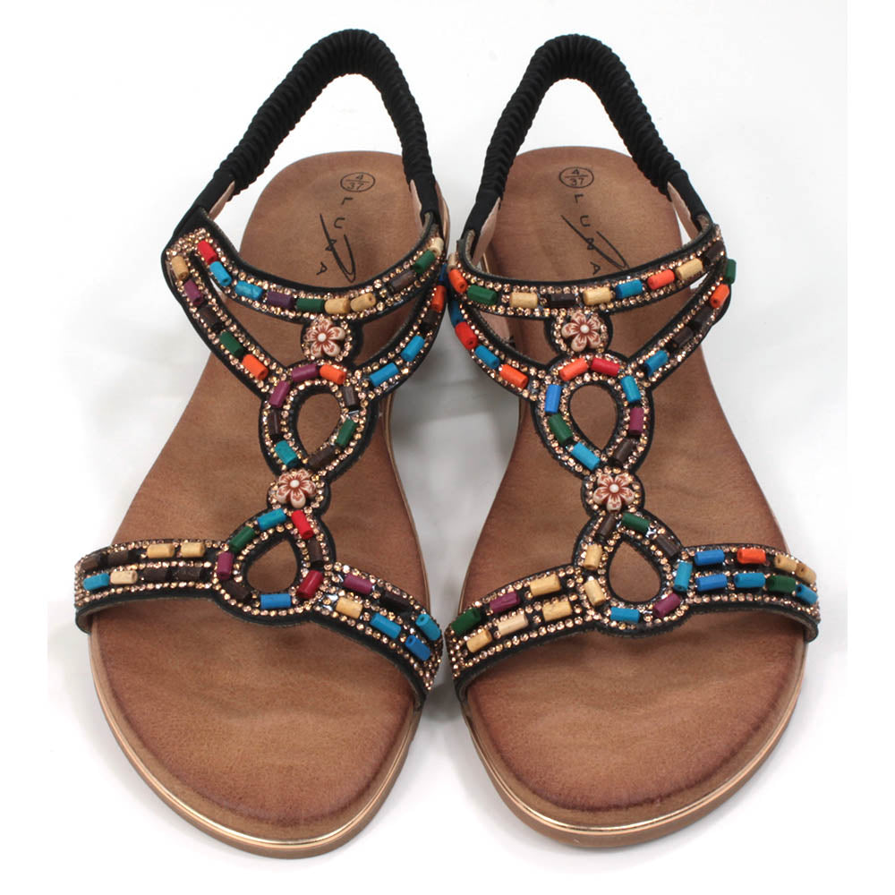 Strappy sandals with elasticated ankle strap in black. Decorated with colourful beads. Tan coloured footbeds. Flats. Front view.