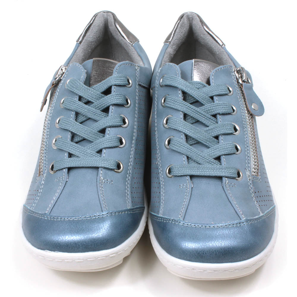 Mid blue trainers with white soles. Matching laces for adjustment and side zip for fitting. Silver detailing on the tongue and at the heels. Front view.