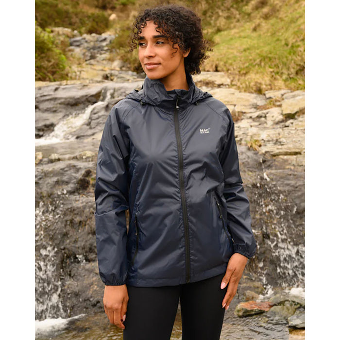 Woman in navy blue lightweight short rainproof coat against rocky terrain.