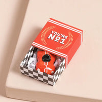 Red object in a checkered box with 'You're No. 1' text on a beige background