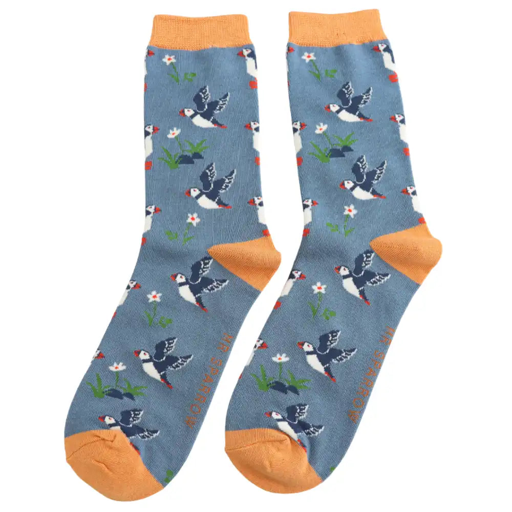 A pair of blue crew socks with flying puffins and yellow heels, cuffs and toes, shown against a plain white background.