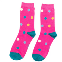 A pair of bright pink crew socks with multicolored polka dots and teal heels and toes, shown against a plain white background.