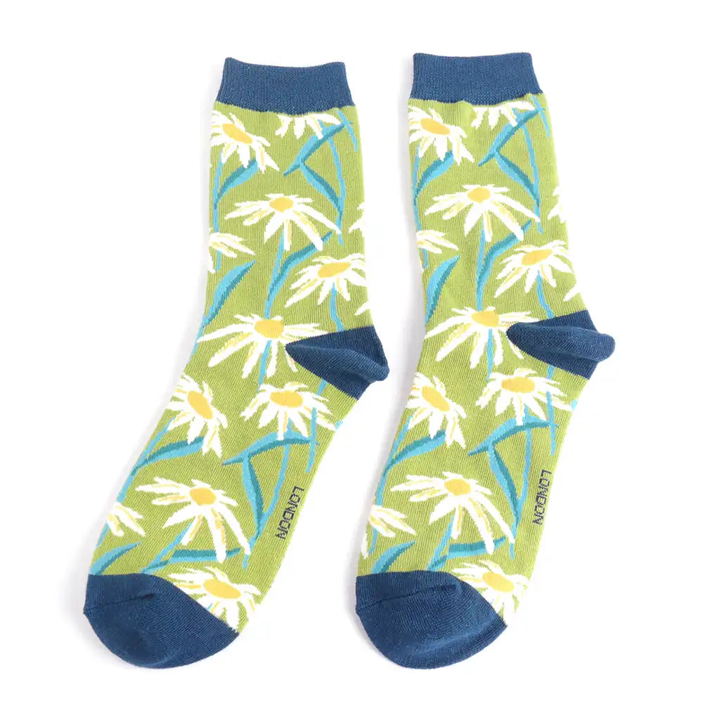 A pair of ankle socks with multiple daisies on a green backgound with navy cuffs, heels and toes.