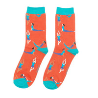 A pair of orange crew socks with yoga poses and turquoise heels, cuffs and toes, shown against a plain white background.
