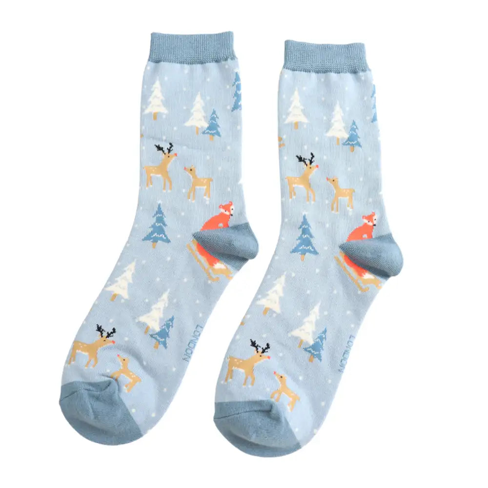 Pair of light blue socks with reindeer and Christmas tree pattern on a white background
