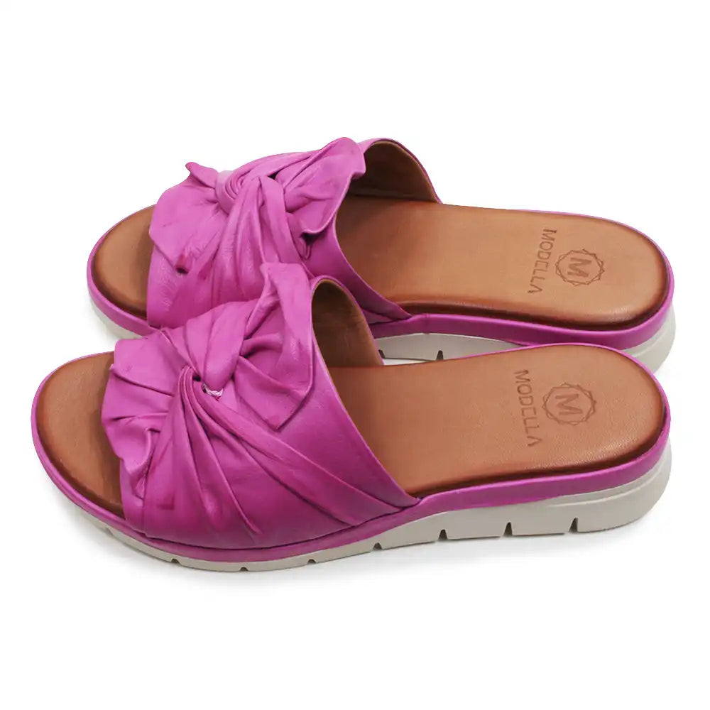 Pink sandals with bow detail on a white background