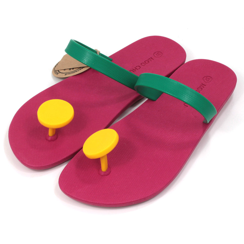 Slider sandals with bright cerise soles, green over the foot strap and large bright yellow 'dot' toe posts. All made from recycled rubber. Angled view.