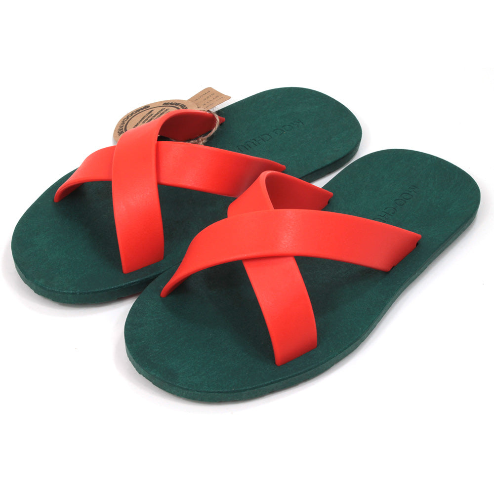 Rubber soled green flip flops. Orange rubber straps crossing the sandals in a cross over the feet. Angled view.